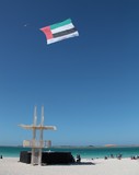 Abu Dhabi public beach National day United Arab Emirates flag towing by Falcon Aviation Services Bell 412 Helicopter